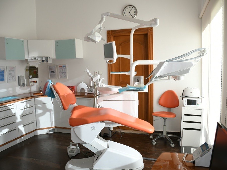 A dental treatment room with a coral chair, lit by a window